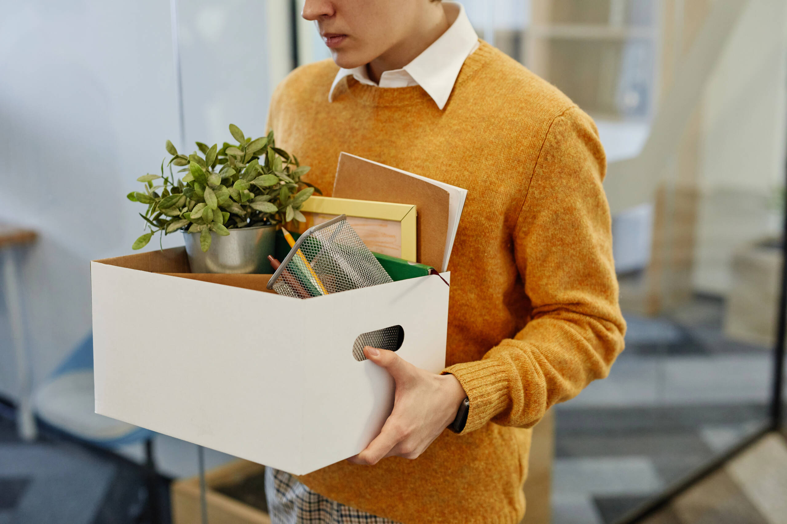Person carrying a box of personal belongings after leaving a workplace