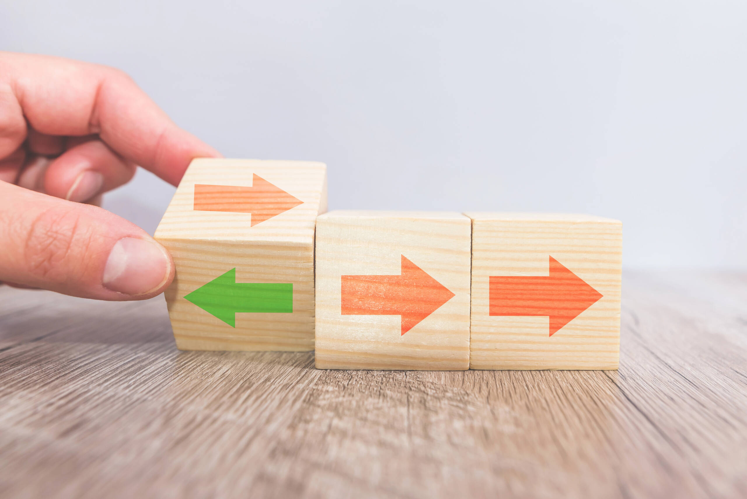 Wooden blocks with arrows pointing in different directions, representing uncertainty and decision-making during career change.