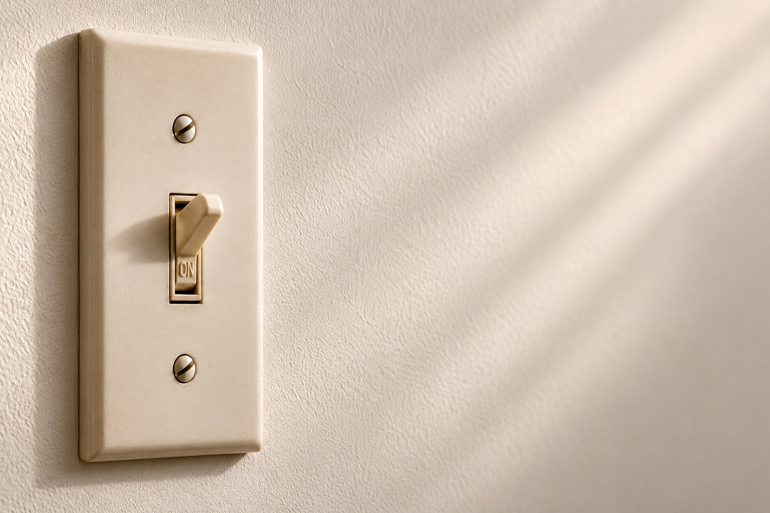 Wall-mounted light switch in the on position against a neutral wall.